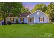 Charming blue home featuring a well-manicured lawn and a welcoming covered entryway at 1938 Dembrigh Ln, Charlotte, NC 28262