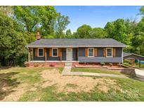 Charming single story home with a brick foundation, gray siding, and lovely wood shutters at 4050 Leafmore St, Concord, NC 28027