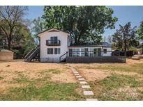 Charming waterfront home featuring a spacious deck and stepping stone pathway to the lawn at 451 S Strand Dr, Norwood, NC 28128