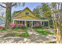 Charming two-story yellow home featuring a welcoming front porch and beautiful landscaping at 505 S South St, Gastonia, NC 28052