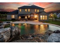Expansive backyard featuring a pool with rock waterfall and covered patio with dining area, perfect for entertaining at 5051 Hyannis Ct, Matthews, NC 28104