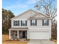Charming two-story home featuring light gray siding, dark blue shutters, and a welcoming front porch with stone accents at 5124 Fireweed Ct, Dallas, NC 28034