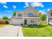 Charming two-story home featuring a covered front porch, attached garage, and well-maintained lawn on a sunny day at 6418 Castlewynd Ct, Charlotte, NC 28212