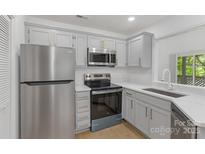 Updated kitchen features stainless steel appliances, gray cabinets with gold pulls, and granite countertops at 6523 Clavell Ln, Charlotte, NC 28210