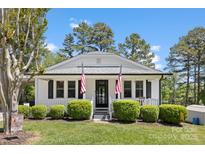Charming single-story home with a well-maintained lawn and inviting front porch adorned with American flags at 8044 Eagle St, Mount Pleasant, NC 28124