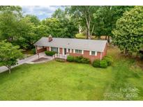 Charming brick home featuring a well-manicured lawn, mature trees, and a cozy front porch at 1307 Armstrong Rd, Belmont, NC 28012