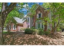 Charming two-story brick and gray home with mature trees and landscaping creating a serene and inviting atmosphere at 15744 Berryfield St, Huntersville, NC 28078
