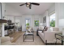Bright living room with a modern ceiling fan, large windows, and an open view of the kitchen at 2138 Revolution Park Dr, Charlotte, NC 28208