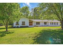 Charming single-story home with mature trees and a lush, green front lawn at 4307 Wrangler Sw Dr, Concord, NC 28027