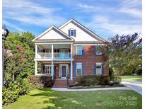 Charming two-story brick home with a covered front porch and lush landscaping under a bright blue sky at 1105 Hoyle Ln, Waxhaw, NC 28173
