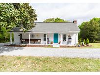 Charming home featuring a welcoming front porch with rocking chairs and a bench, complemented by a blue front door and landscaped yard at 1165 Old Salisbury Concord Rd, Concord, NC 28025