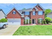 Beautiful brick home featuring manicured lawn, arched windows, black shutters and attached two-car garage at 2003 Dataw Ln, Indian Trail, NC 28079
