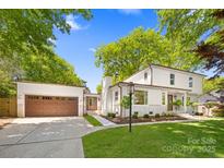 Charming white home featuring an attached garage, manicured lawn, and professionally landscaped front yard at 2411 Ainsdale Rd, Charlotte, NC 28226