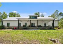 Charming farmhouse featuring a white exterior, metal roof, and inviting front porch with chairs and swing at 29268 Pennington Rd, Albemarle, NC 28001