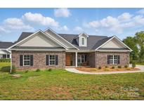 Charming brick home boasts a well-manicured lawn and a welcoming front porch, perfect for relaxing at 3013 Isle Ln, Monroe, NC 28110