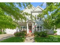 Charming two-story home featuring a red front door, manicured lawn, and an inviting porch with an American flag at 5301 Meadowcroft Way, Fort Mill, SC 29708