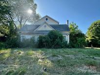 Exterior shot of home with overgrown lawn and mature trees on a sunny day at 6000 S Main St, Salisbury, NC 28147