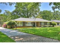 Charming brick home featuring a lush green lawn, mature trees, and a welcoming walkway leading to the front door at 751 Lansdowne Rd, Charlotte, NC 28270