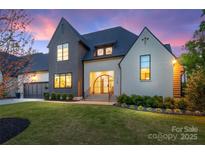 Elegant home with a manicured lawn, striking architecture, and a grand entrance, bathed in the soft hues of dusk at 1118 Jefferson Dr, Charlotte, NC 28270