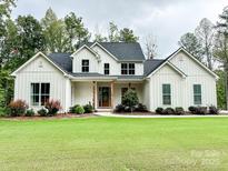 Charming white farmhouse-style home with a well-manicured lawn and inviting front porch at 1123 Fern Hill Rd, Mooresville, NC 28117