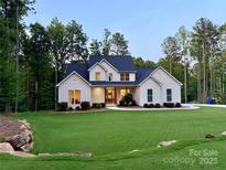 Stunning white home with a dark roof, beautiful lawn, and lush landscaping at 1123 Fern Hill Rd, Mooresville, NC 28117