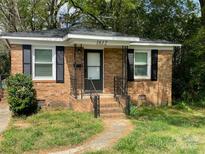 Charming brick home featuring black shutters, a cozy porch, and a well-defined walkway at 1612 Russell Ave, Charlotte, NC 28216