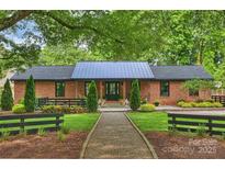 Charming brick home with a metal roof and beautifully landscaped front yard at 742 Lansdowne Rd, Charlotte, NC 28270