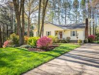 Charming yellow home with brick chimney and colorful, mature landscaping at 8801 Chinaberry Ln, Concord, NC 28027