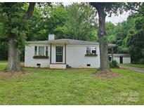 Charming single-story home with white brick, dark door and window boxes nestled among mature trees at 13131 601 S Hwy, Midland, NC 28107