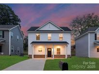 Charming two-story home featuring a covered front porch and a well-maintained lawn at dusk at 1841 Bear St, Charlotte, NC 28213