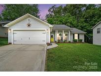 Charming single-story home with a well-manicured lawn, attached garage, and inviting front porch with rocking chairs at 7417 Chidley Dr, Charlotte, NC 28269