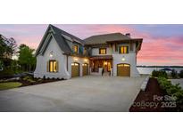 Stunning waterfront home with painted brick, copper accents, and a three-car garage at sunset at 7679 Rabbit Cir, Denver, NC 28037