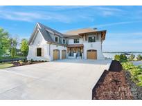 Stunning exterior of a white brick home featuring a three-car garage and spacious concrete driveway at 7679 Rabbit Cir, Denver, NC 28037