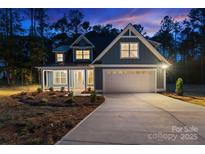 Charming home with a manicured lawn, a two-car garage, and a cozy front porch, illuminated against a twilight sky at 925 Twin Lakes Rd, Rock Hill, SC 29732