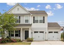 Charming two-story home with a 2 car garage, black shutters and a well-manicured lawn and blooming plants at 1218 Juddson Dr, Waxhaw, NC 28173