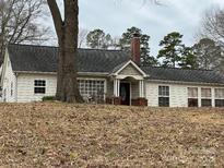 Charming single-story home with neutral siding, a dark roof, and a brick chimney, nestled on a leafy lot at 14131 Lucia Riverbend Hwy, Mount Holly, NC 28120