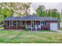 Charming brick home featuring a well-maintained front yard and covered porch with beautiful landscaping at 221 Delview Dr, Cherryville, NC 28021