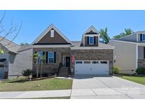 Charming brick home featuring an attached two-car garage, well-maintained lawn, and patriotic American flag at 2333 Talon Point Cir, Fort Mill, SC 29715