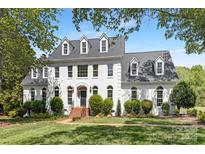Stately white home featuring dormer windows, black door, brick walkway, and manicured lawn at 426 Walden Trl, Waxhaw, NC 28173