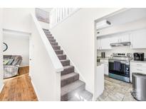 Bright staircase featuring carpeted stairs, white walls, and direct access to a modern kitchen space at 7407 Mystic Ln, Charlotte, NC 28227