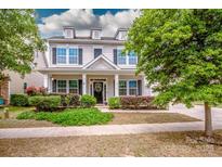 Charming two-story home with a well-manicured lawn, dormer windows, and inviting front porch at 10707 Charmont Pl, Huntersville, NC 28078