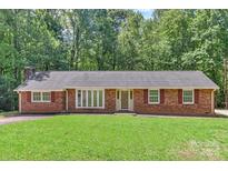 Charming brick ranch home with a lush green lawn and mature trees surrounding the property at 182 Freedom Mill Rd, Gastonia, NC 28052