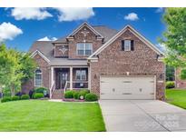 Charming two-story brick home featuring a well-manicured lawn and attached two-car garage at 525 Chase Prairie Ln, Waxhaw, NC 28173