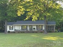Single-story home with a cozy porch and screened-in patio, framed by mature trees at 5317 Friendly Baptist Ch Rd, Indian Trail, NC 28079