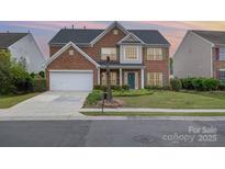 Charming two-story red brick home with attached garage and well-manicured front lawn at 5803 Lindley Crescent Dr, Indian Trail, NC 28079