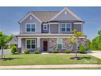 Two-story home featuring stone accents, gray siding, manicured lawn, and professional landscaping at 6113 Russo Ct, Lancaster, SC 29720
