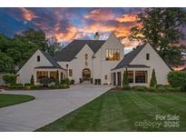 Striking white brick home with dark trim, manicured lawn, and lush landscaping at sunset at 7861 Live Oaks Dr, Denver, NC 28037