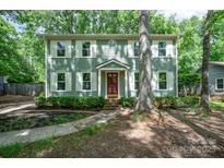 Charming two-story home with sage green siding, white shutters and a red front door surrounded by lush landscaping at 8936 Rittenhouse Cir, Charlotte, NC 28270