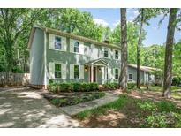 Side view of a sage green two-story home with a well-maintained yard and mature trees providing shade at 8936 Rittenhouse Cir, Charlotte, NC 28270