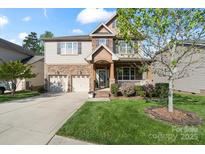 Charming two-story home with stone accents, manicured lawn, attached two-car garage and a welcoming covered front porch at 10116 Garman Hill Dr, Charlotte, NC 28214